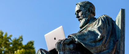 The statue of Ezra Cornell holds a laptop